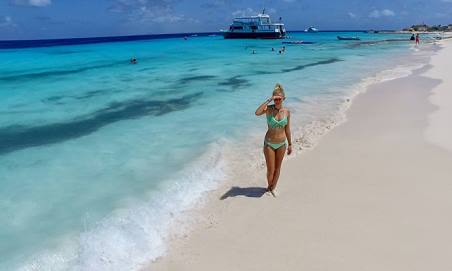 Girl is walking on the white sandy beach of Klein Curacao